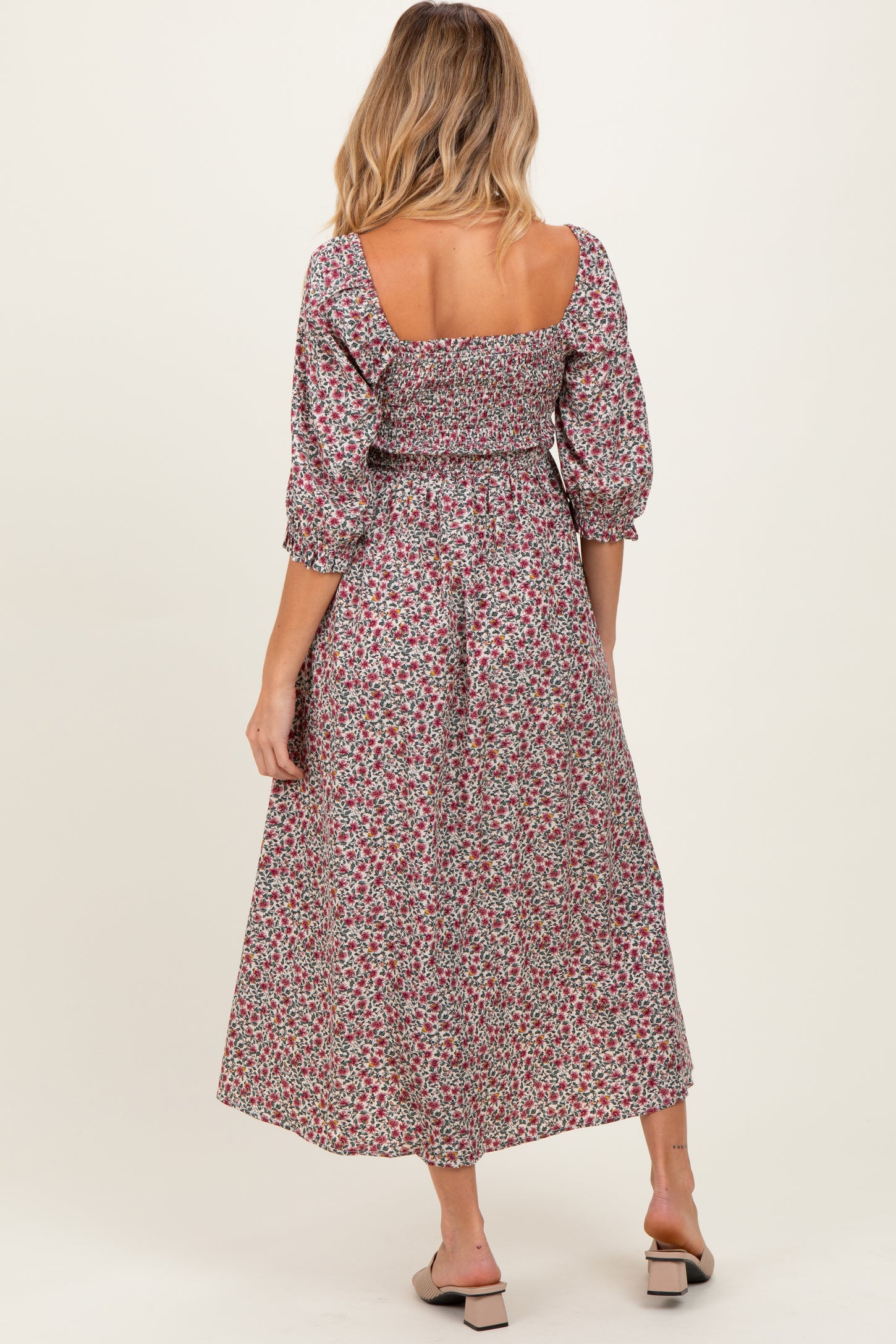 woman wearing a floral maternity dress with puff sleeves and a cinched waist, showing a baby bump from the back