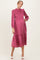 woman wearing a pink smocked maternity dress with long sleeves and a flowy skirt, showing her baby bump