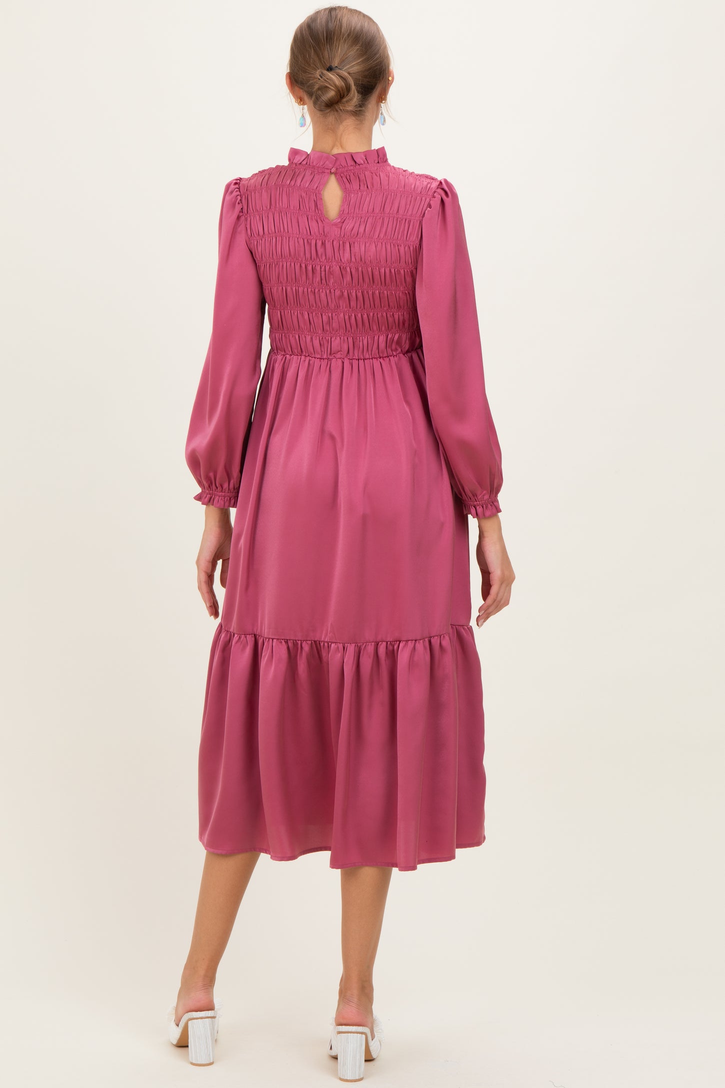 woman wearing a burgundy long sleeve maternity dress with smocked bodice and tiered skirt, showing back view