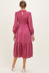 woman wearing a burgundy long sleeve maternity dress with smocked bodice and tiered skirt, showing back view
