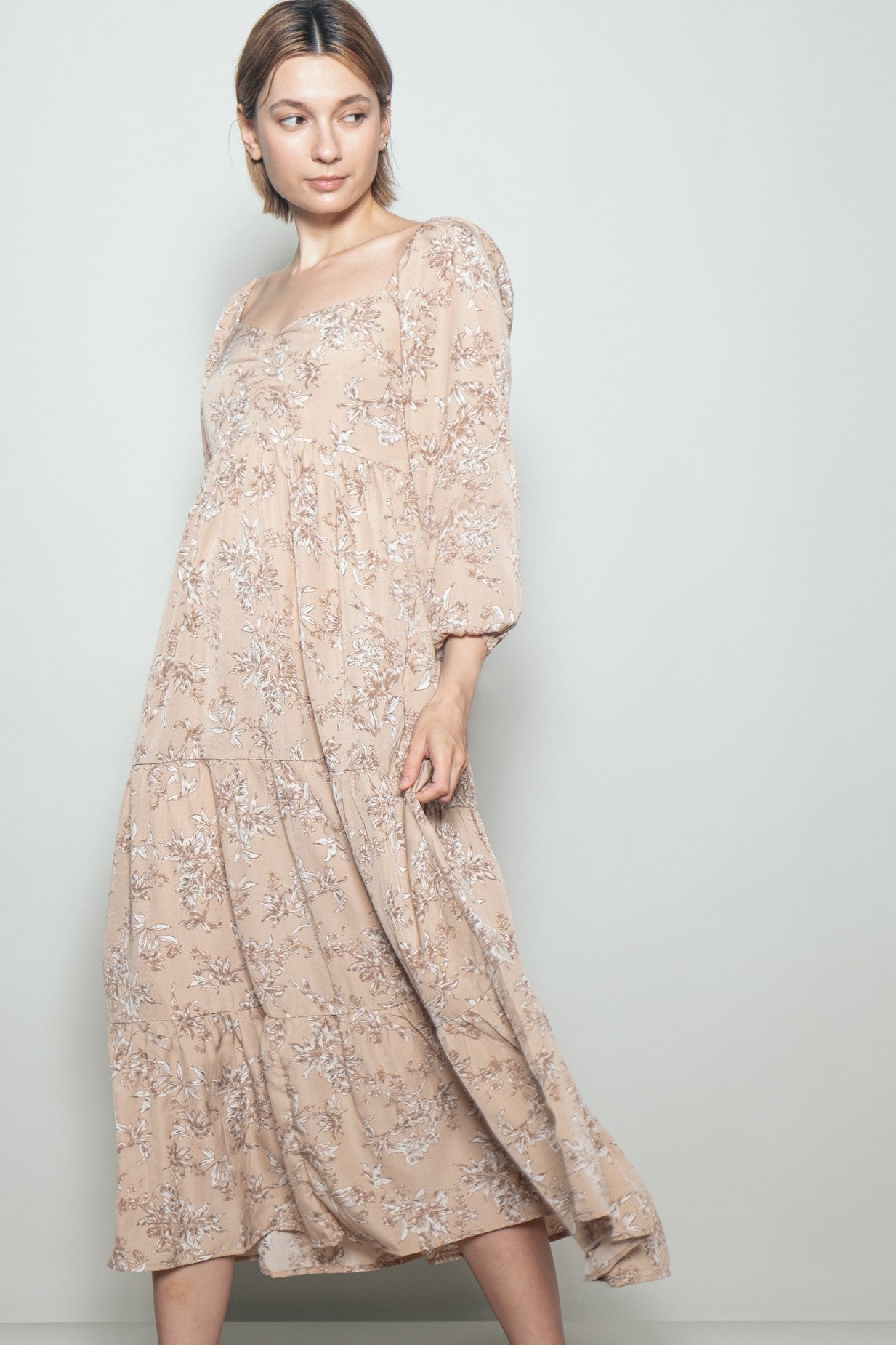 woman wearing a light beige floral maxi dress with puffed sleeves and a square neckline