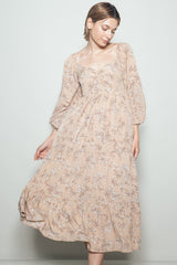 woman wearing a beige floral midi dress with puff sleeves, twirling slightly against a light background