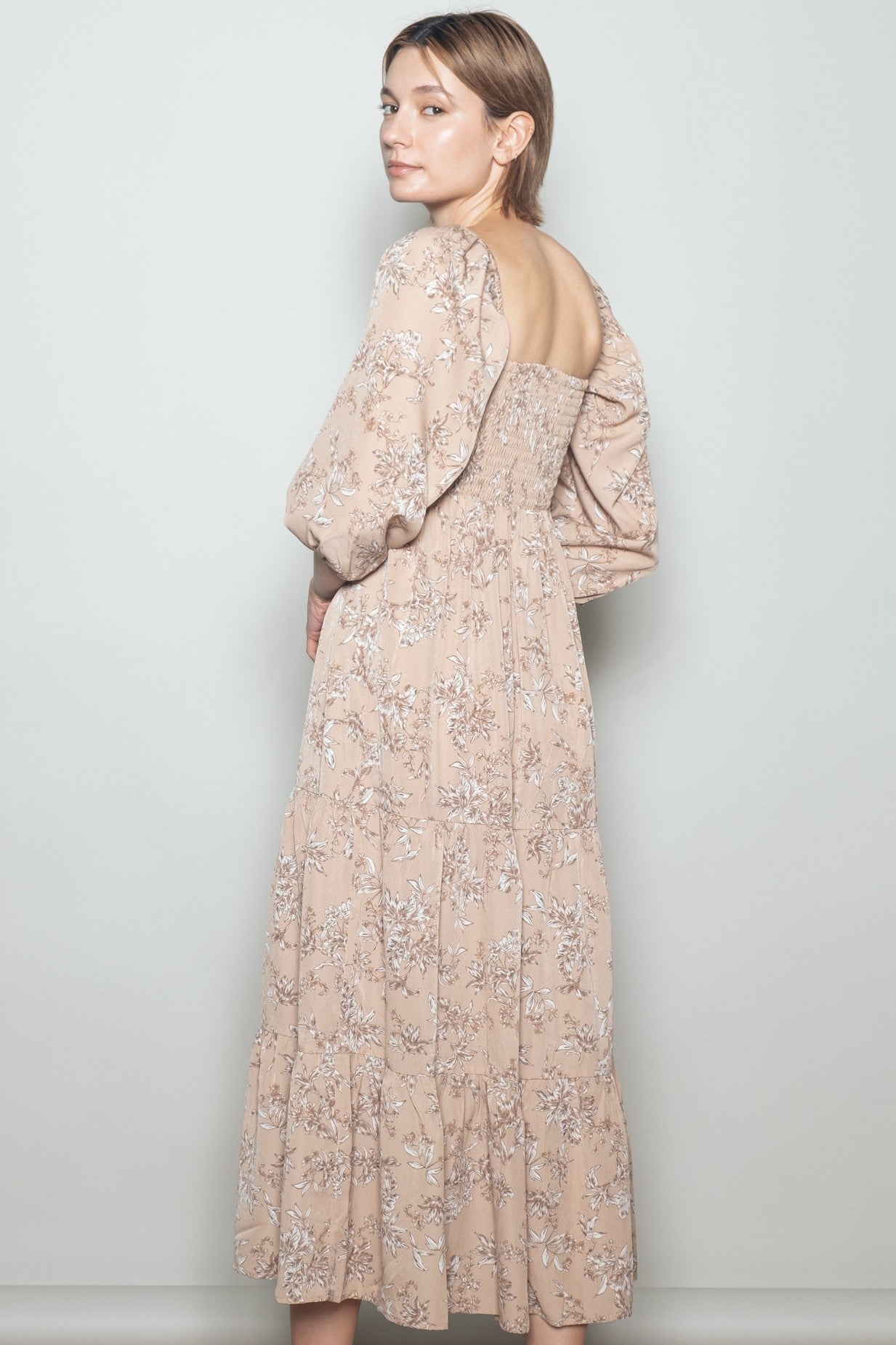 woman wearing a floral print beige maxi dress with puff sleeves and a smocked back