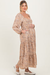 woman wearing a floral long sleeve maternity dress with a tiered skirt and holding her baby bump