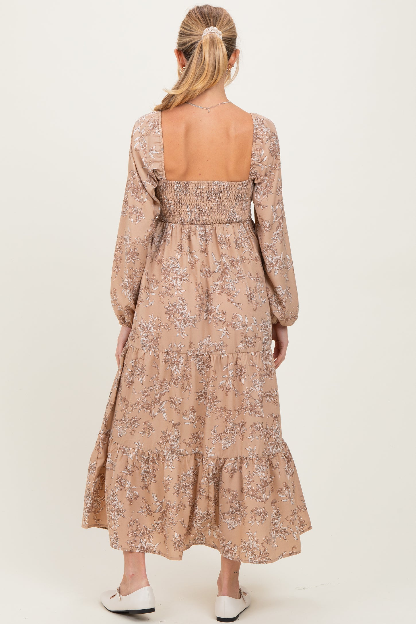 woman wearing a floral maternity maxi dress in beige with a smocked back and long sleeves