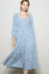 woman wearing a light blue floral long sleeve maxi dress with a square neckline and flowy skirt