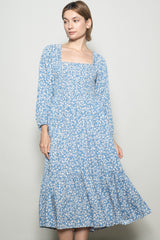 woman wearing a light blue floral long sleeve midi dress with a square neckline and tiered skirt