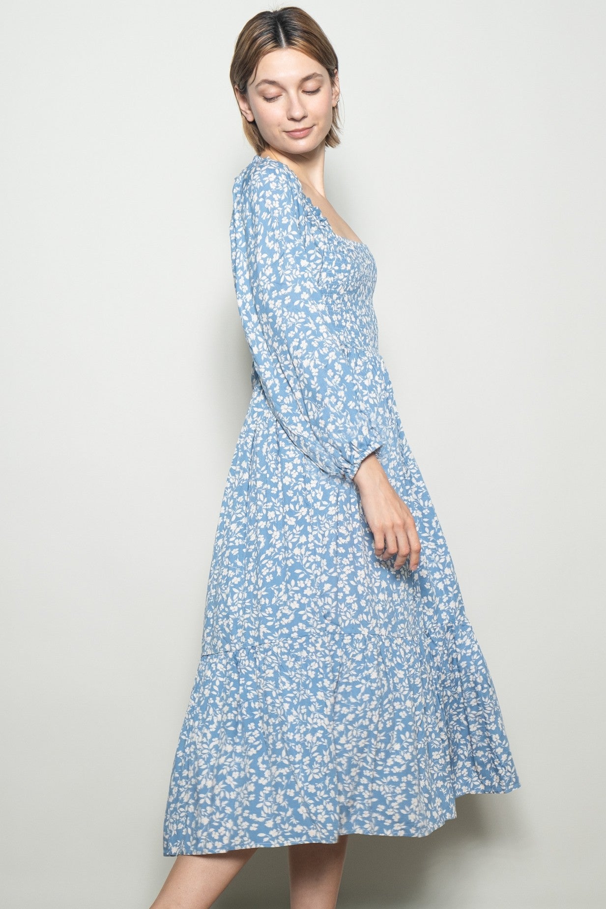 woman wearing a light blue floral midi dress with puff sleeves and a square neckline