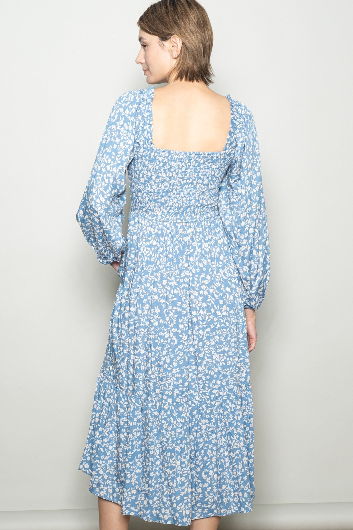 woman wearing a light blue floral midi dress with a square back and long puff sleeves