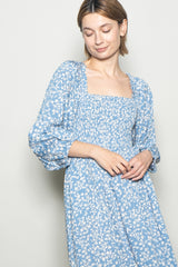 woman wearing a blue floral print dress with a square neckline and puffed sleeves