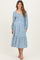 woman wearing a light blue floral maternity dress with a square neckline and long sleeves, posing with a visible baby bump