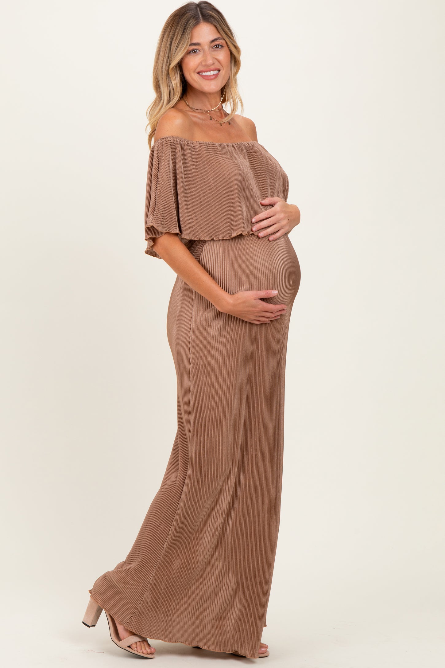 woman wearing a brown off-the-shoulder ribbed maternity dress and holding her baby bump