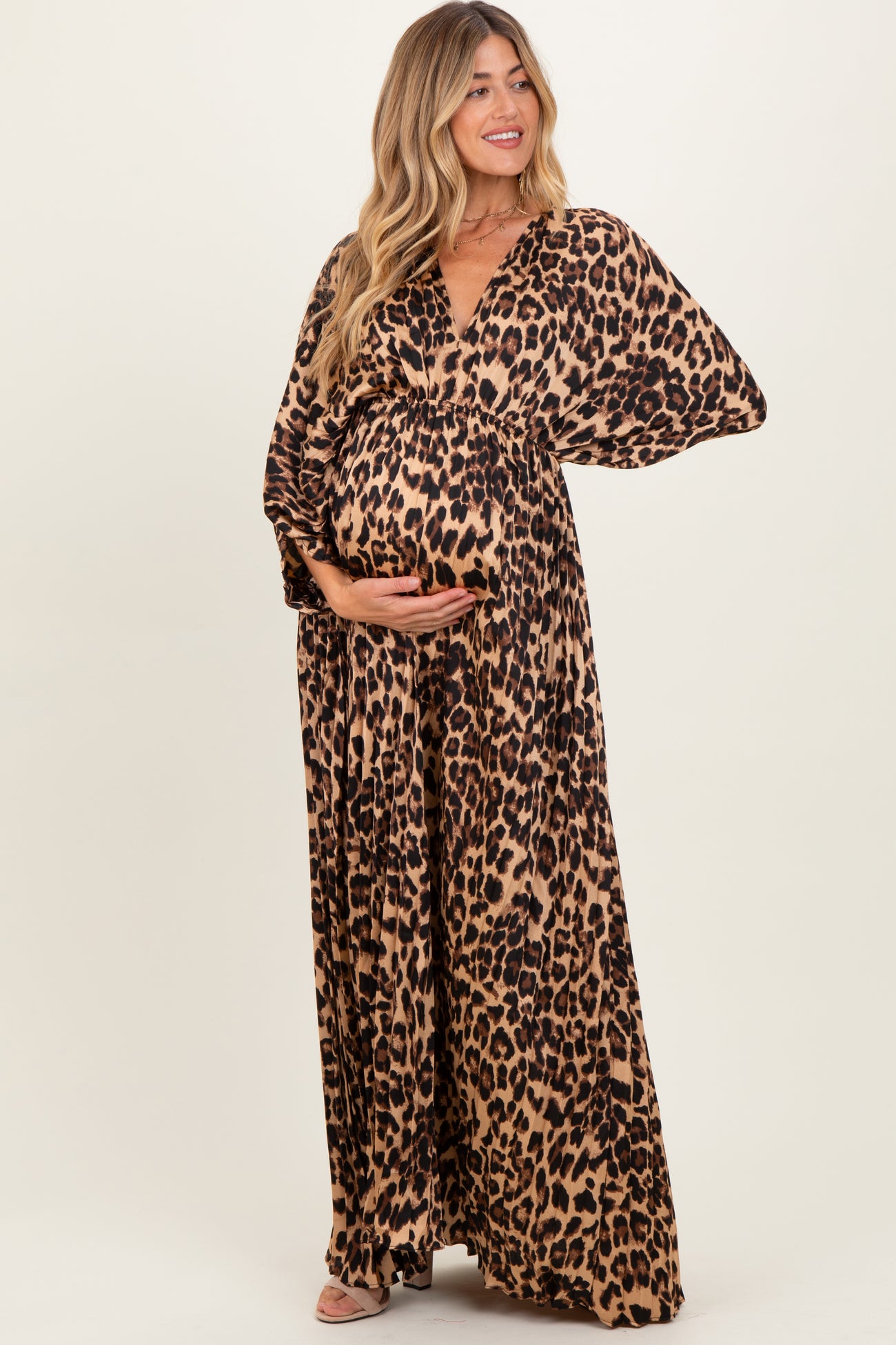 woman wearing a leopard print maternity maxi dress and holding her baby bump