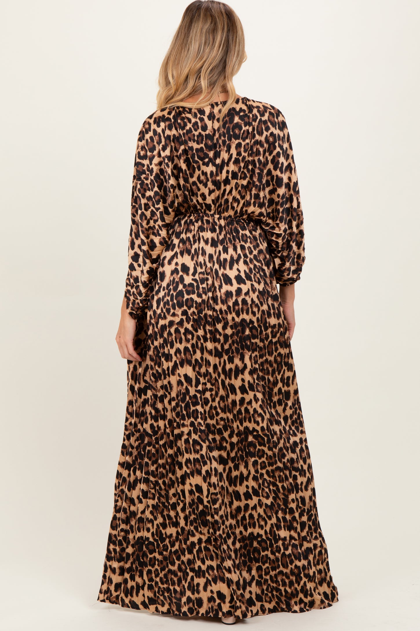 woman wearing a leopard print maternity maxi dress with long sleeves and a tied waist, showing her baby bump