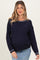 woman wearing a navy blue cable knit maternity sweater with white trim and a visible baby bump