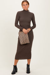 woman wearing a brown long sleeve turtleneck midi dress and holding a leopard print clutch bag