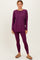 woman wearing a dark purple long sleeve top and matching leggings, standing barefoot