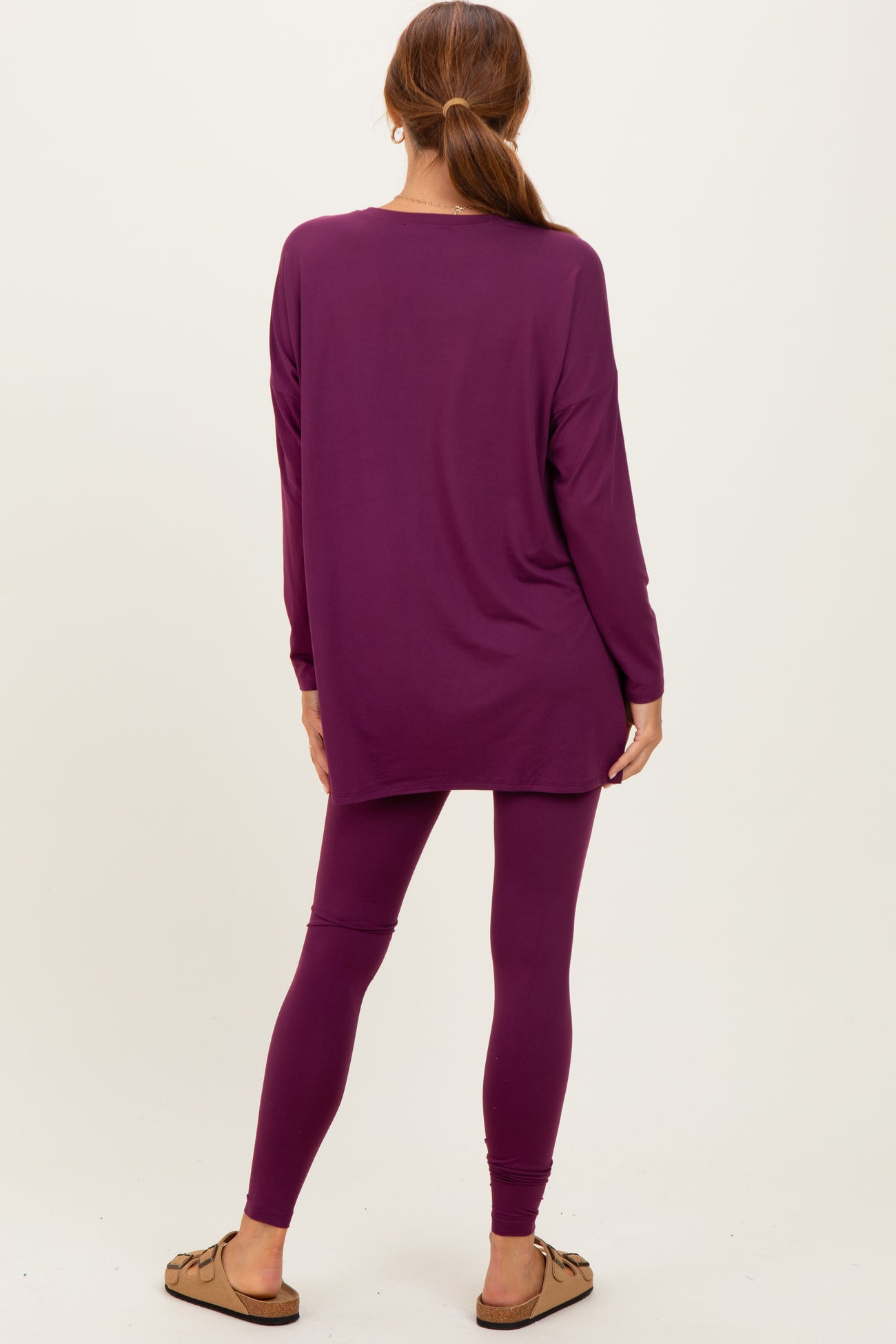 woman wearing a long sleeve purple tunic top and matching purple leggings, viewed from the back
