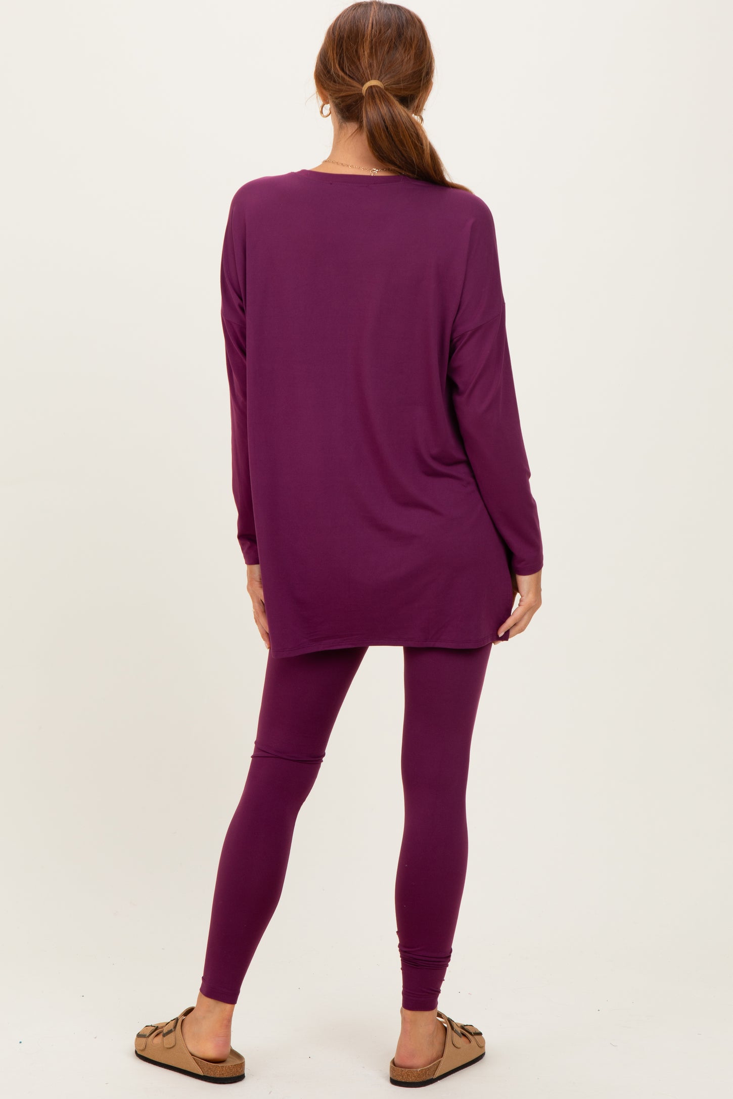 woman wearing a long sleeve purple tunic top and matching purple leggings, viewed from the back