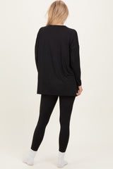 woman wearing a black oversized long sleeve top with black leggings and white socks, viewed from the back