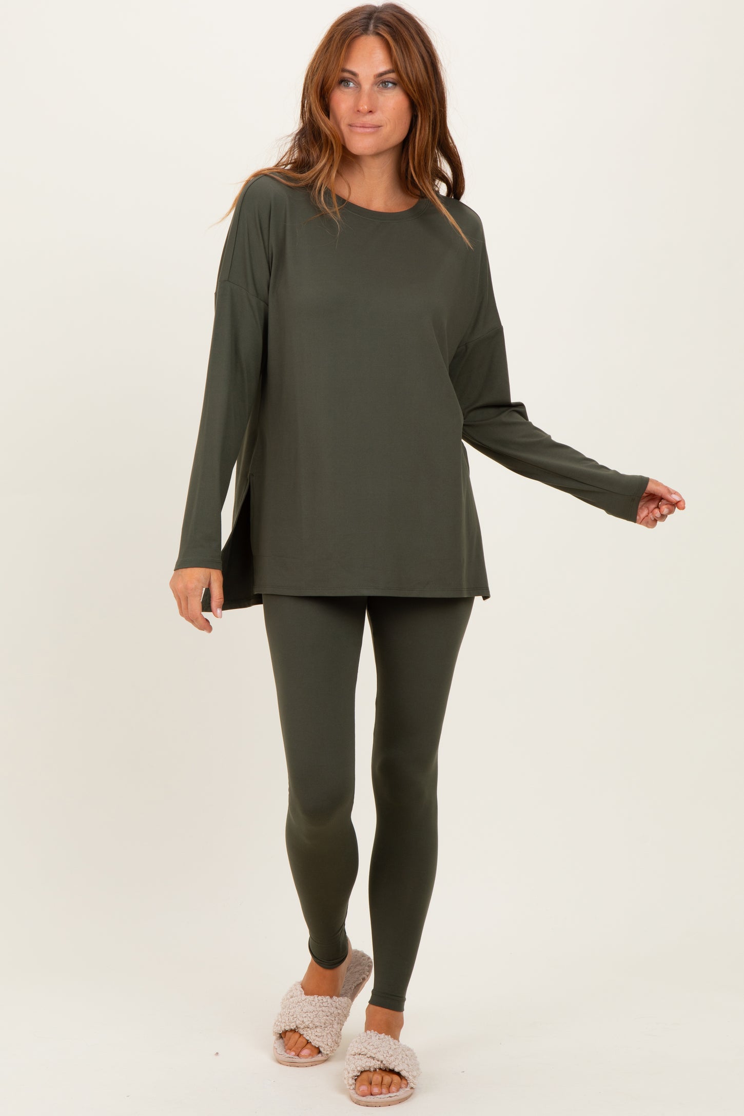 woman wearing an olive green long sleeve top and matching leggings, styled casually with plush slippers