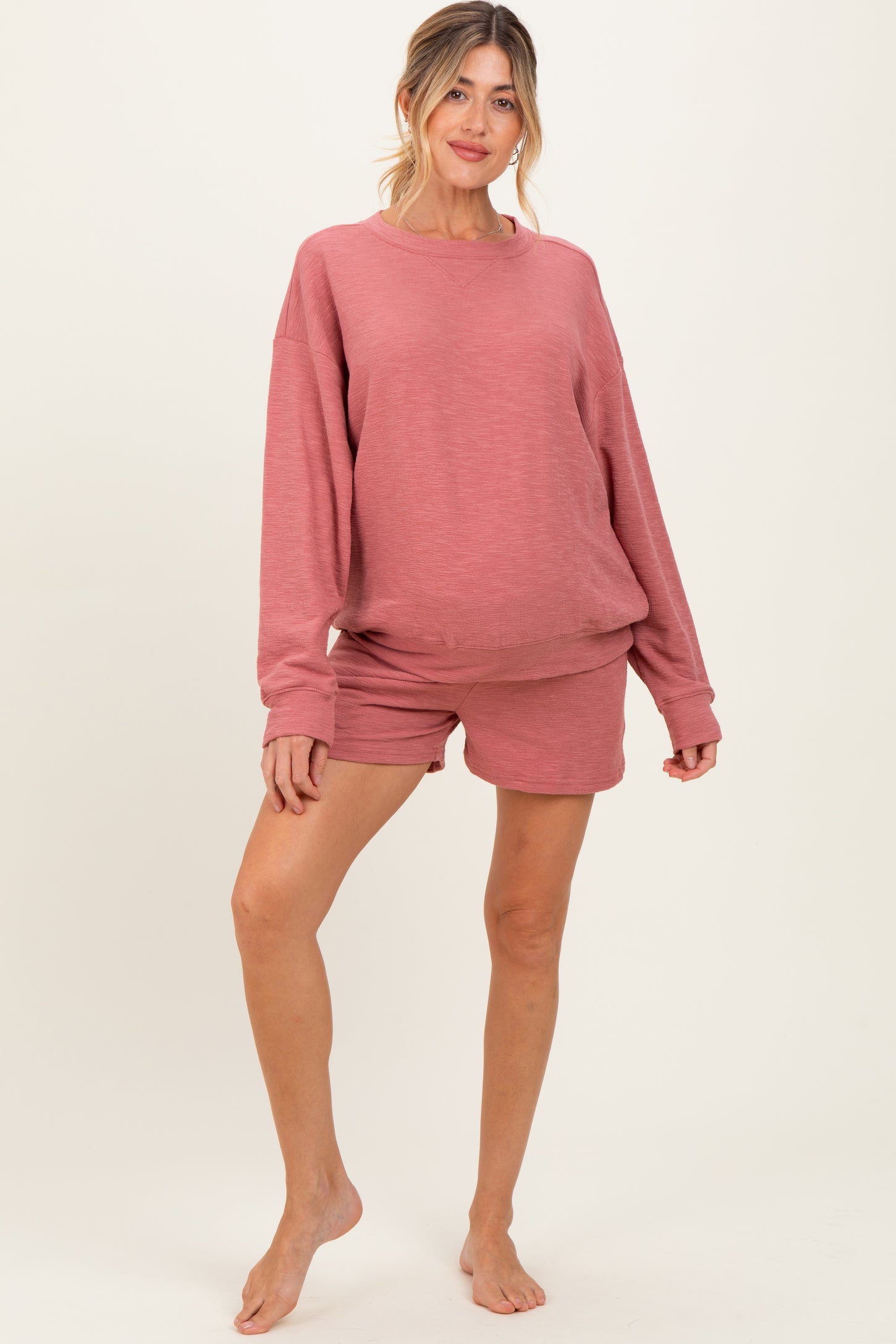 woman wearing a dusty rose maternity sweatshirt and matching shorts, showing her baby bump