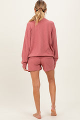 woman wearing a rose pink loose-fit maternity sweatshirt and matching shorts, showing her back