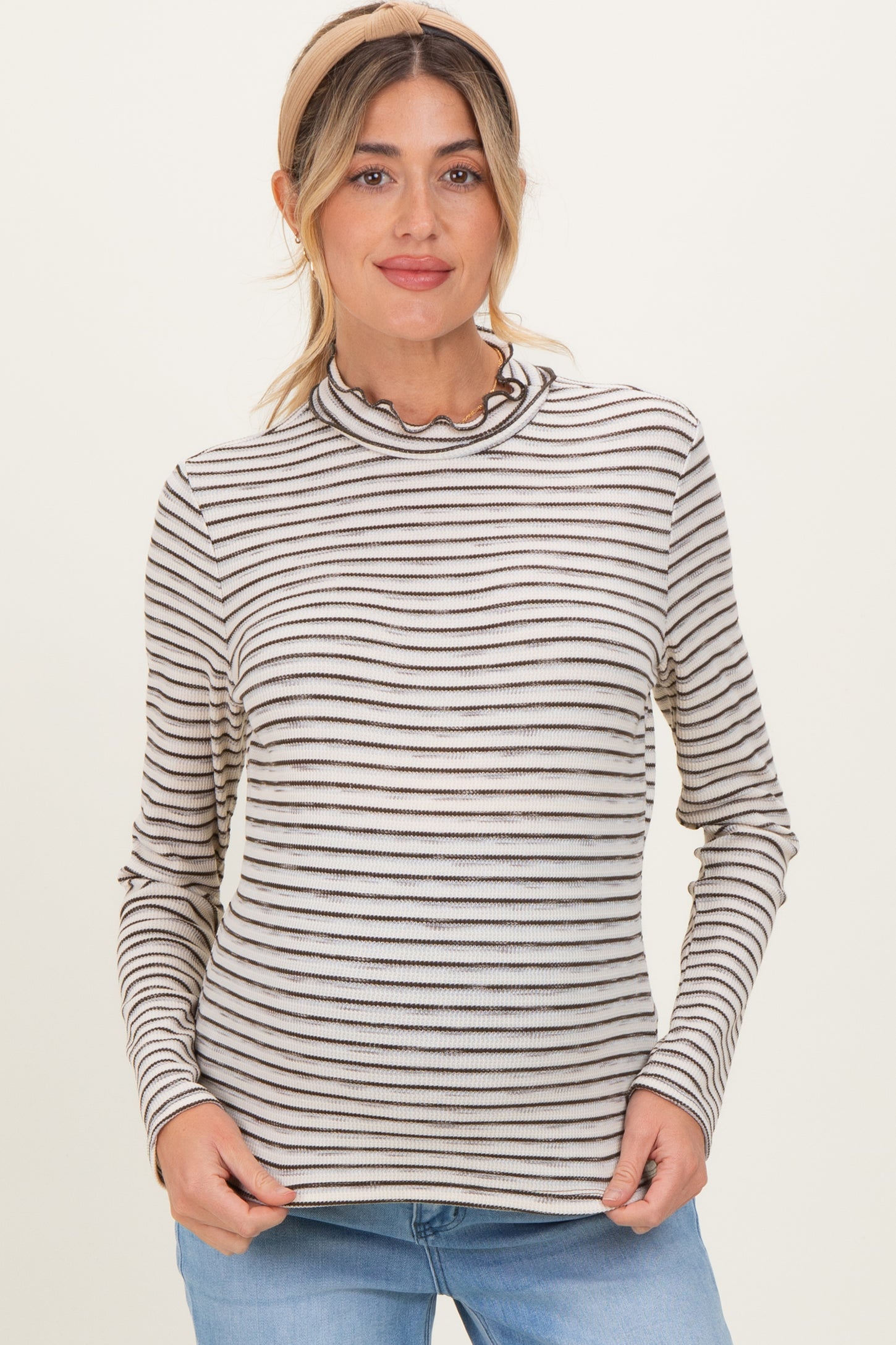 woman wearing a striped maternity top with a ruffled neckline and long sleeves, smiling at the camera