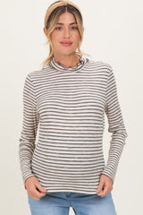 woman wearing a striped maternity top with a ruffled neckline and long sleeves, smiling at the camera