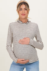 woman wearing a striped long sleeve maternity top with a ruffled neckline and holding her baby bump