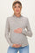 woman wearing a striped long sleeve maternity top with a ruffled neckline and holding her baby bump