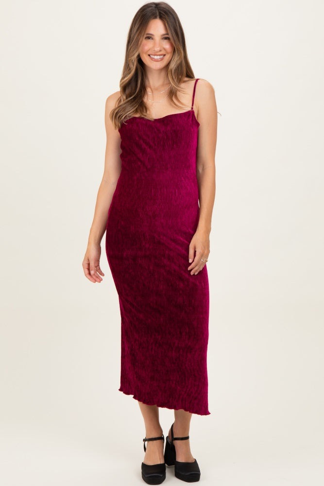 woman wearing a burgundy maternity maxi dress with spaghetti straps and a fitted silhouette