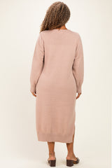 woman wearing a light pink long sleeve sweater dress with a slit at the hem and back detailing