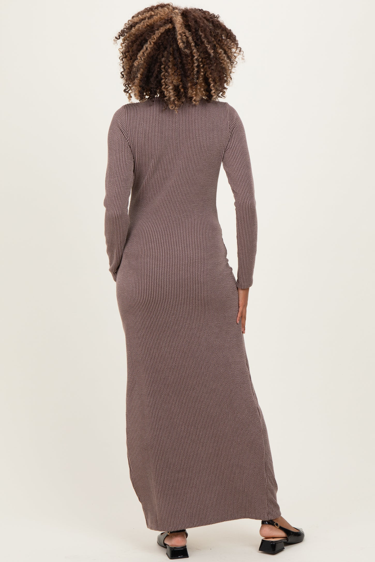 woman wearing a long sleeve brown and cream striped maternity maxi dress, showing the back view