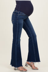 woman wearing dark blue flared maternity jeans, showcasing a visible baby bump and a stylish frayed hem