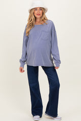 woman wearing a lavender oversized maternity top with a pocket and blue flared maternity jeans, showing her baby bump