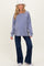 woman wearing a lavender oversized maternity top with a pocket and blue flared maternity jeans, showing her baby bump