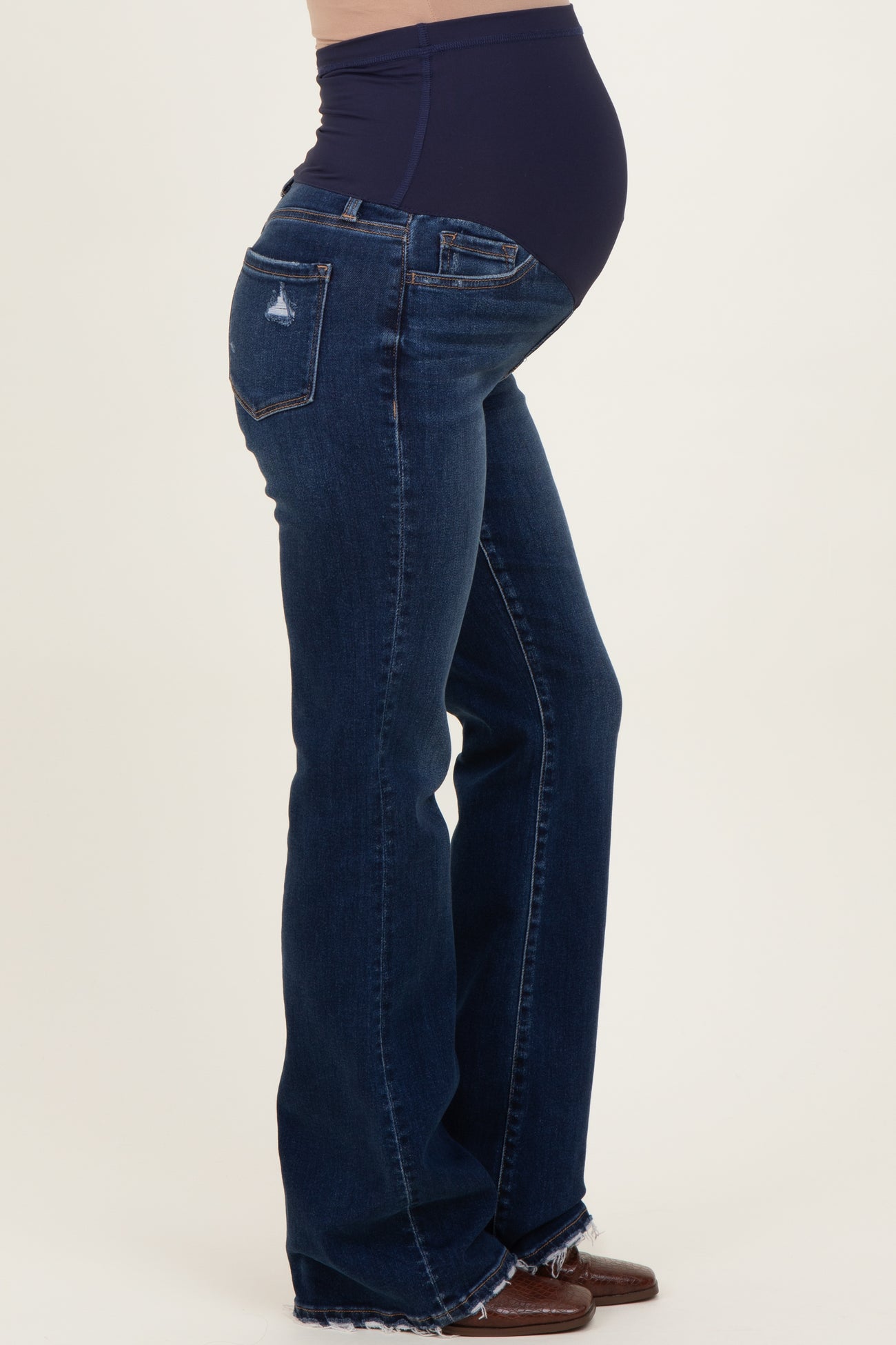 woman wearing dark blue maternity flared jeans with a high waistband and visible baby bump