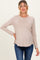 woman wearing a light beige long sleeve maternity top and showing her baby bump while posing