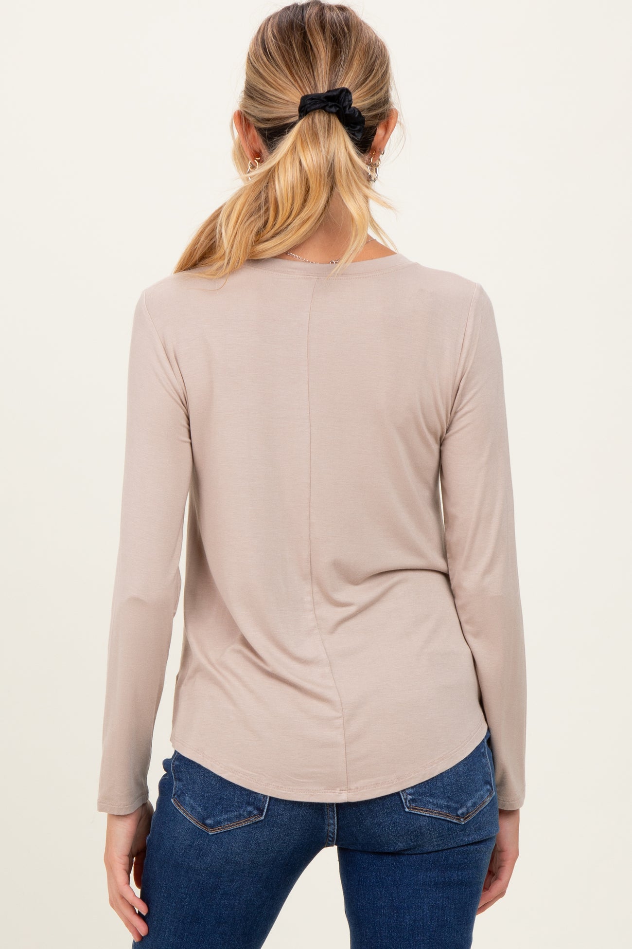 woman wearing a light taupe long sleeve maternity top, view from the back, styled with jeans