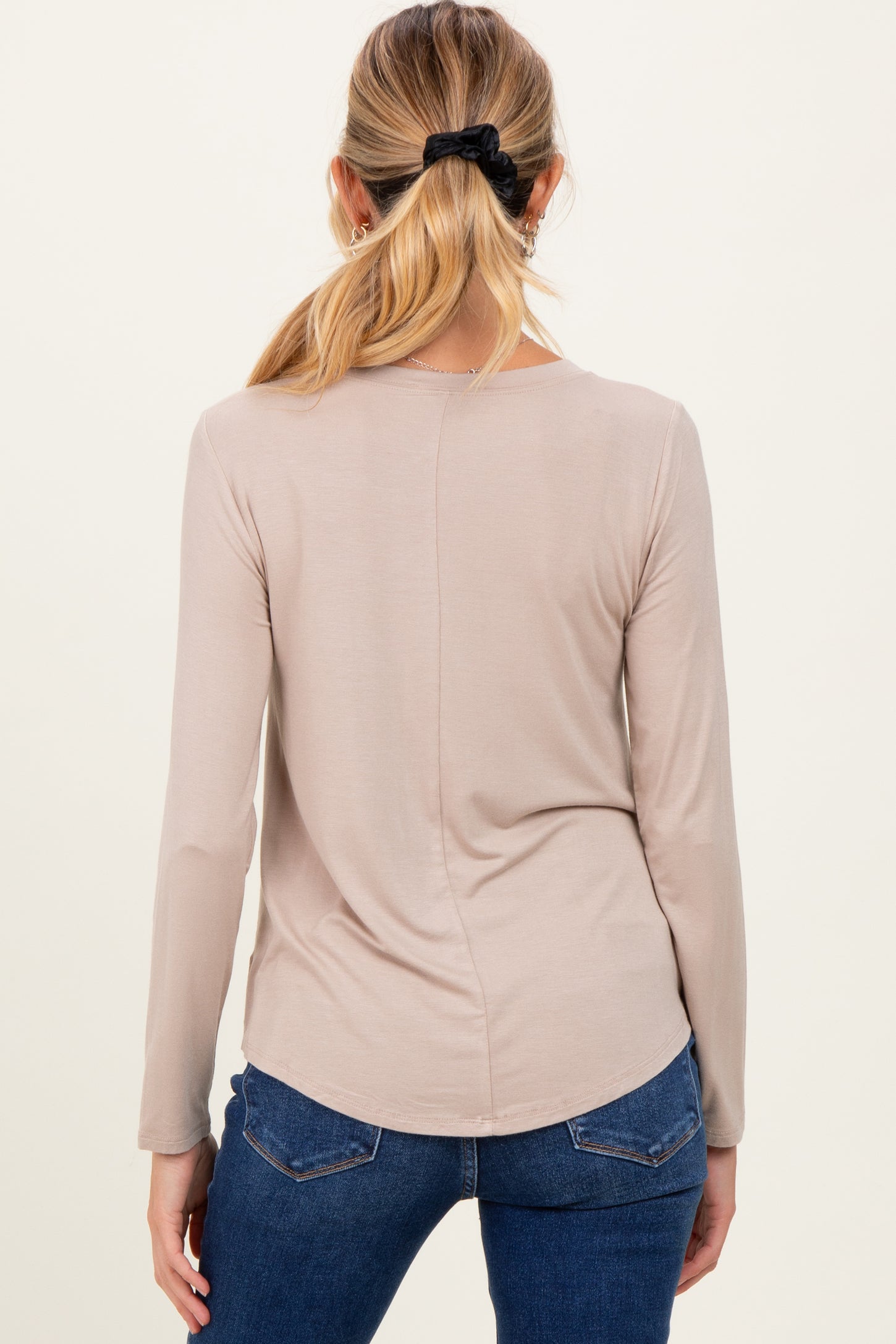 woman wearing a light taupe long sleeve maternity top, view from the back, styled with jeans