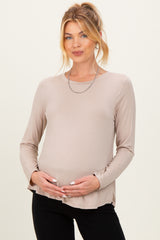 woman wearing a light taupe long sleeve maternity top and holding her baby bump