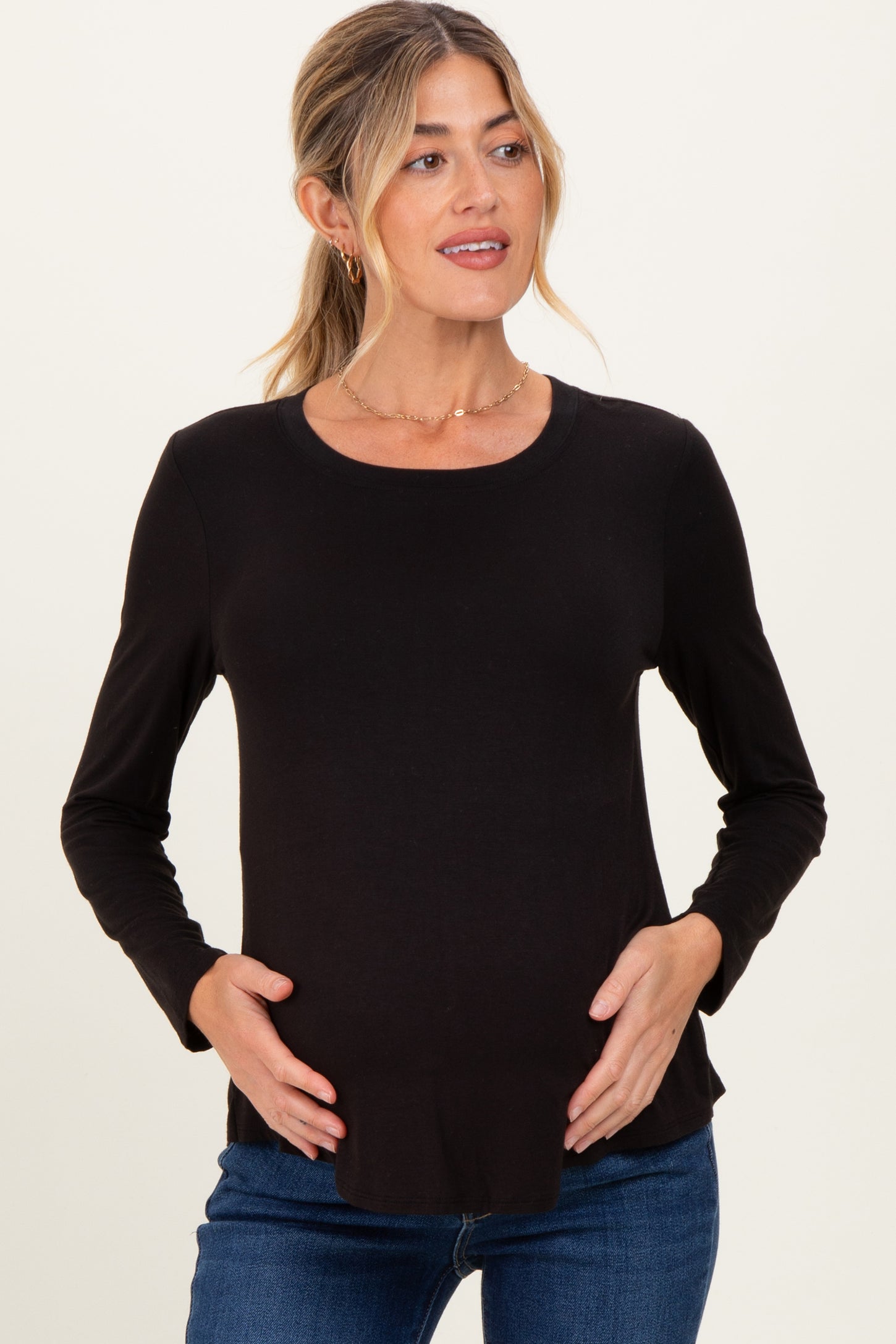 woman wearing a black long sleeve maternity top and holding her baby bump