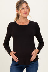 woman wearing a black long sleeve maternity top and holding her baby bump