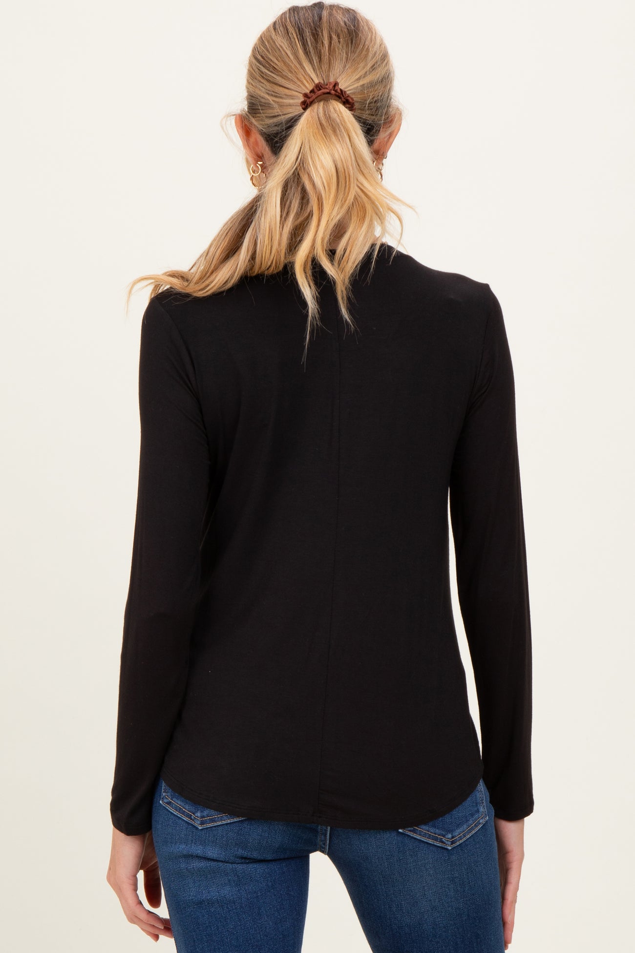 woman wearing a black long sleeve maternity top, view from the back with a sleek design and fitted style