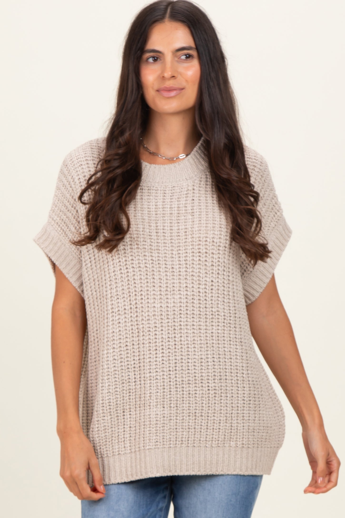woman wearing a beige oversized knitted sweater with short sleeves and a relaxed fit