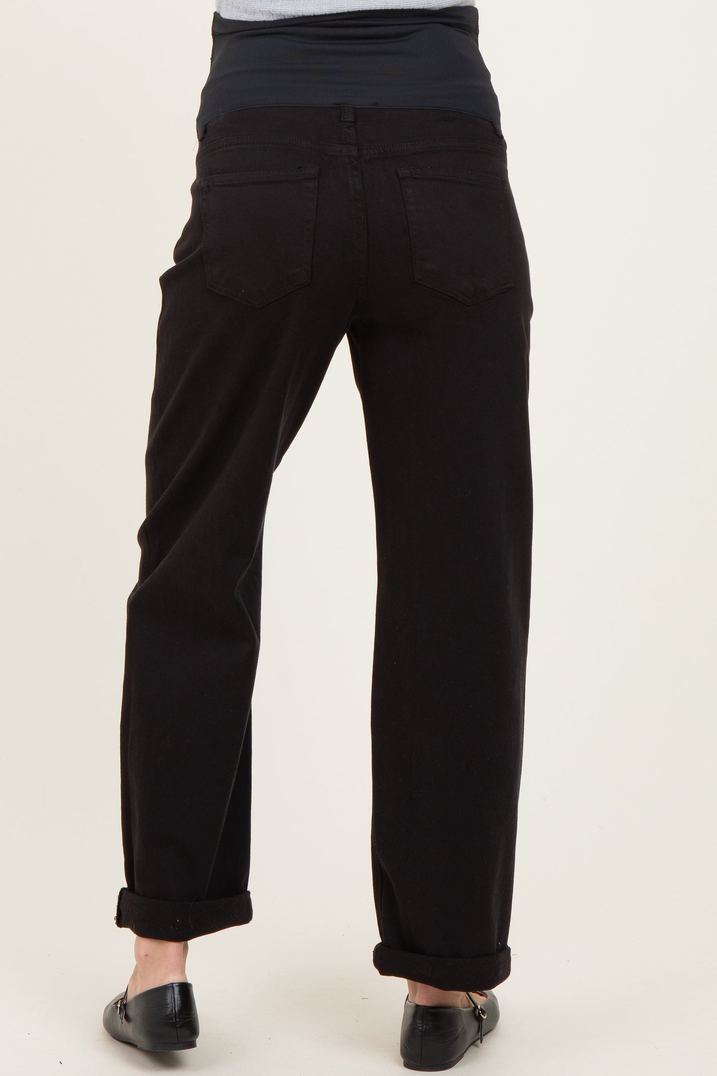 woman wearing black maternity jeans with a rolled hem and a stretchy navy waistband, showing the back view