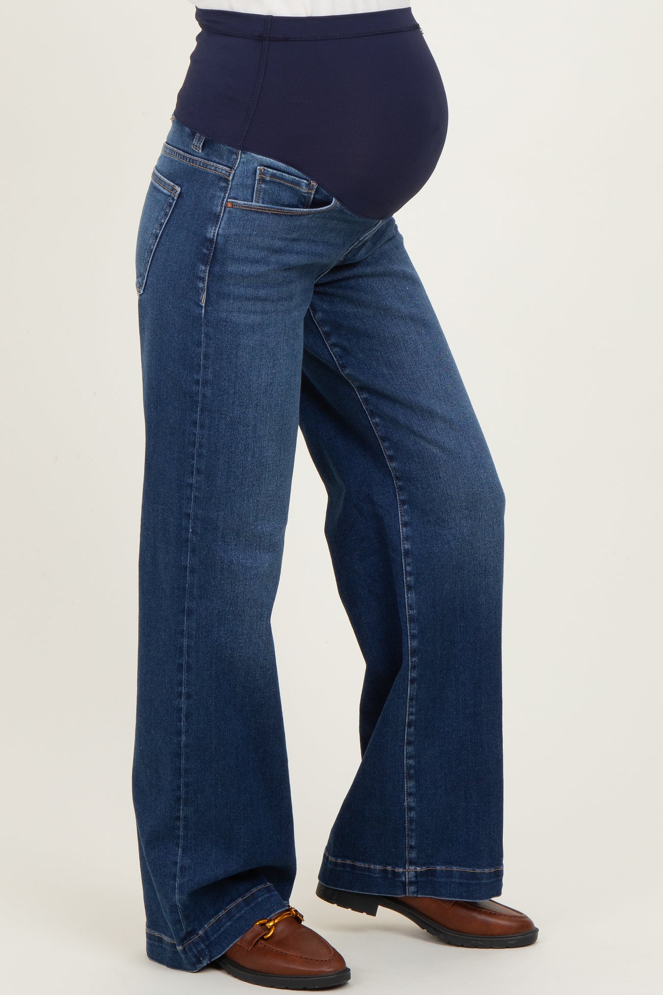 woman wearing dark blue maternity jeans with a supportive belly panel, styled with a wide leg design