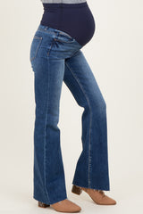 woman wearing blue maternity flared jeans with a dark waistband, showing her baby bump while standing sideways