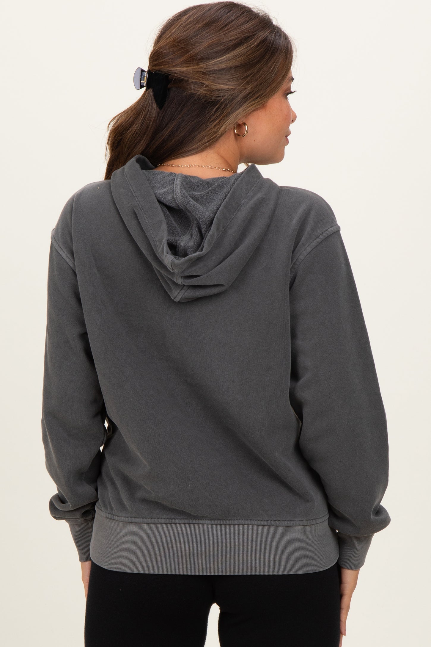 woman wearing a dark gray maternity hoodie with a relaxed fit and a hood, showing the back view